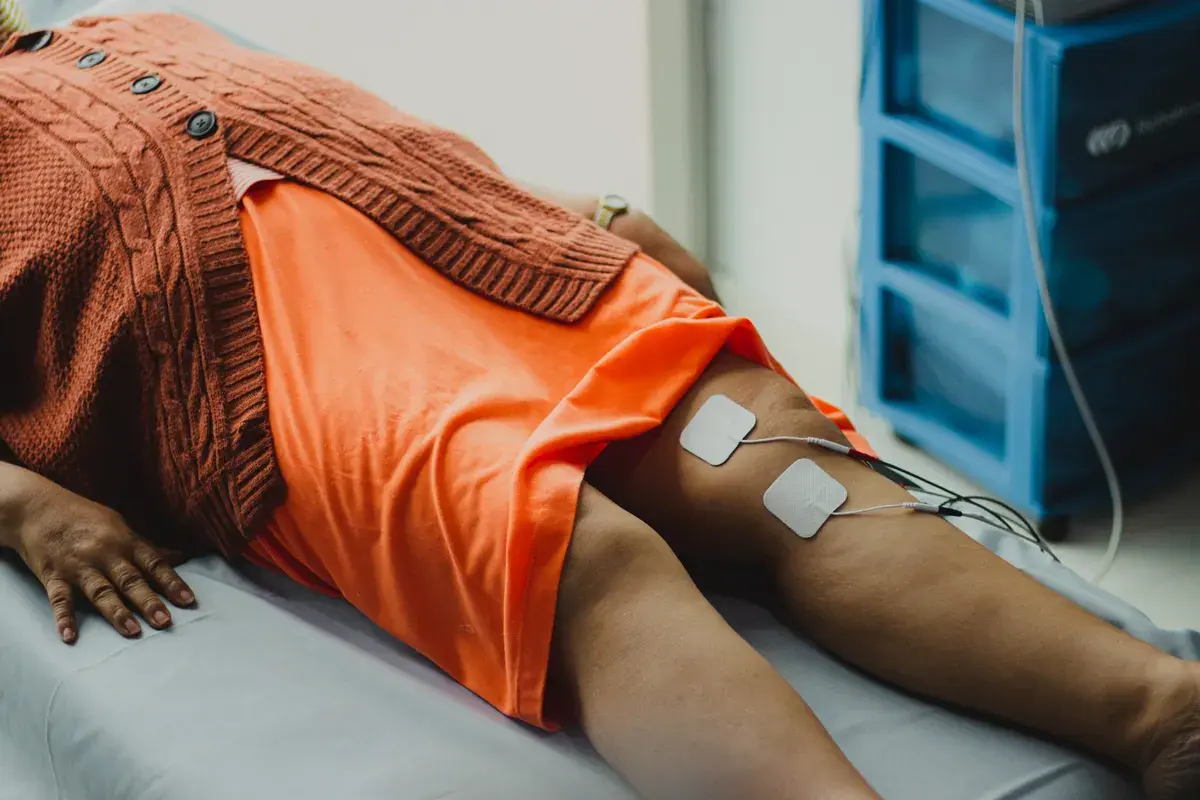 Person lying down wearing an orange shorts with electrode pads attached to their legs connected to wires