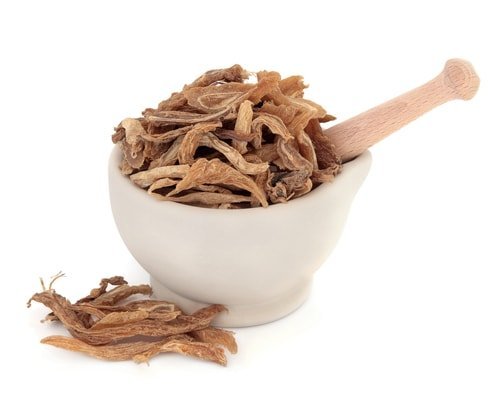 Dried Chinese herbs in a white mortar with a pestle
