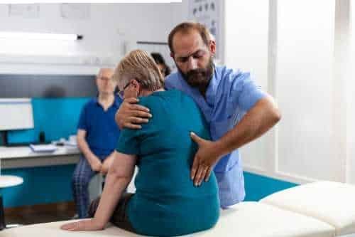 Practitioner supporting a patient’s back in a clinic