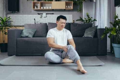 Man sitting on the floor holding his knee