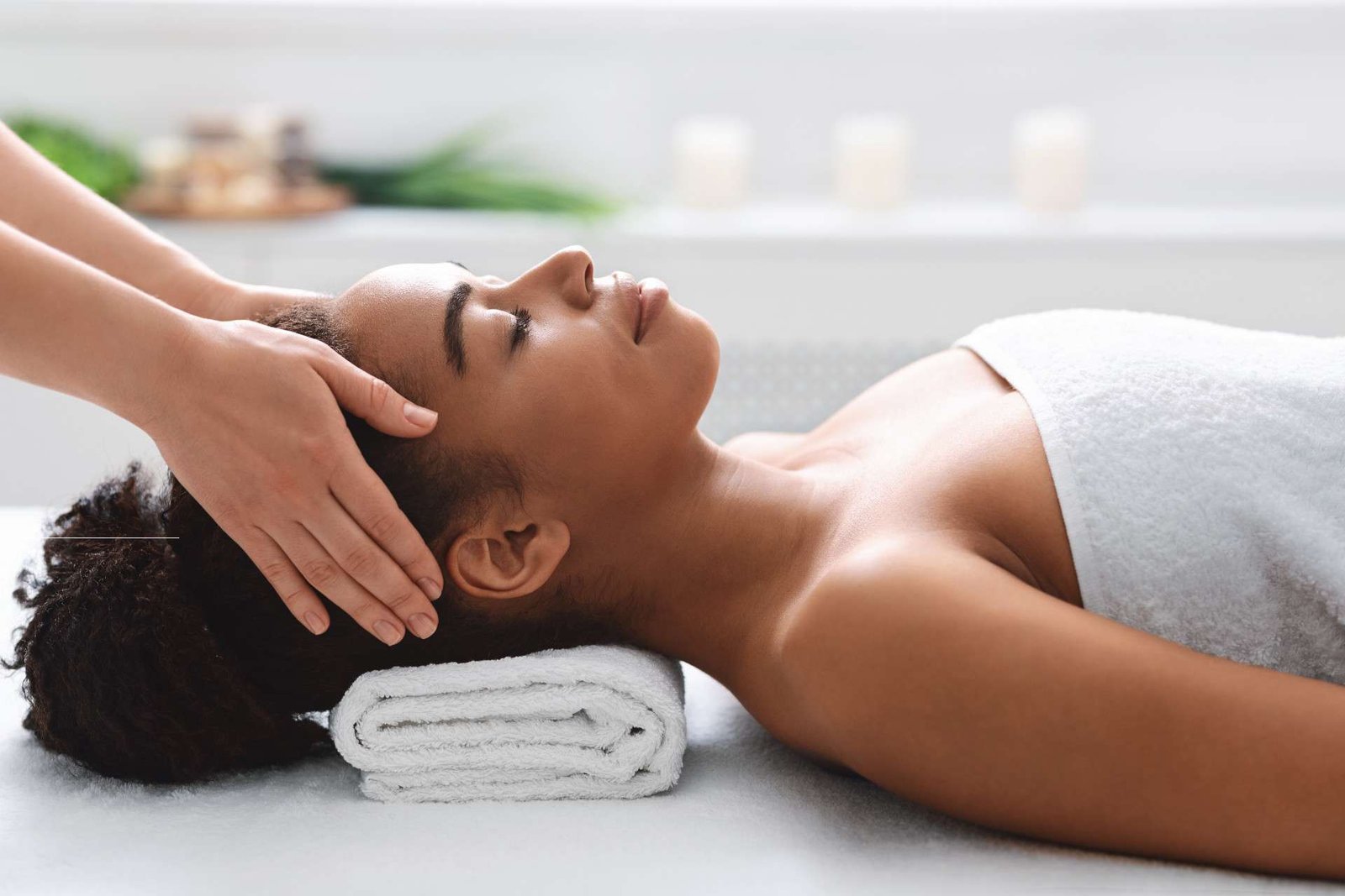 Therapist massaging the head of a woman lying on a treatment table