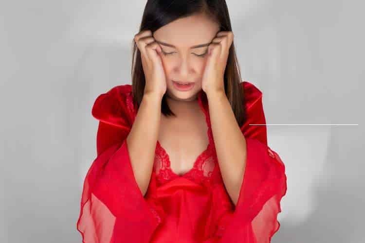 Woman in red holding her head in distress