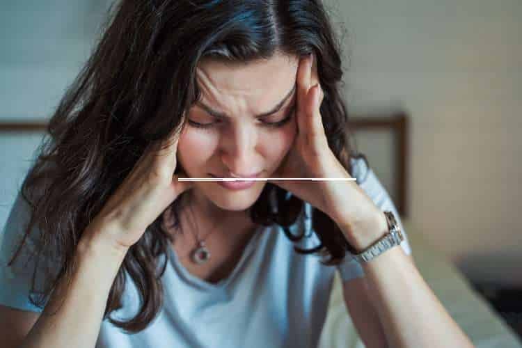 Woman holding her head with her eyes closed
