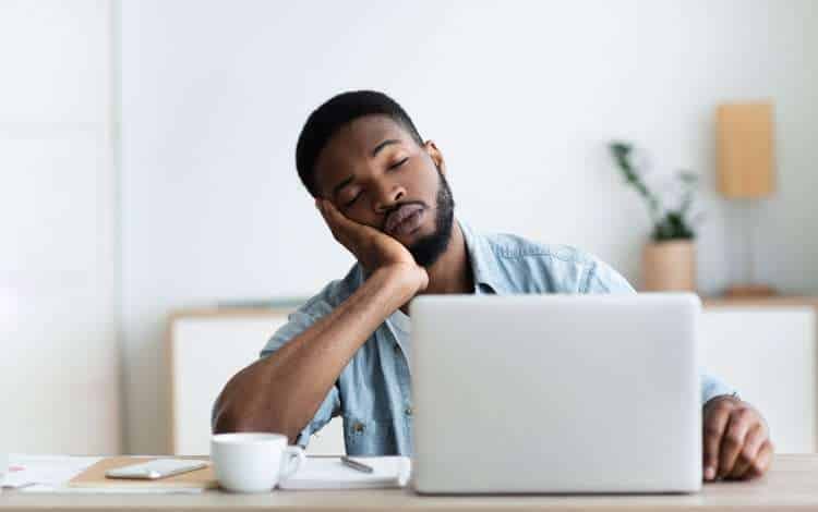 Man at a laptop resting his head on his hand