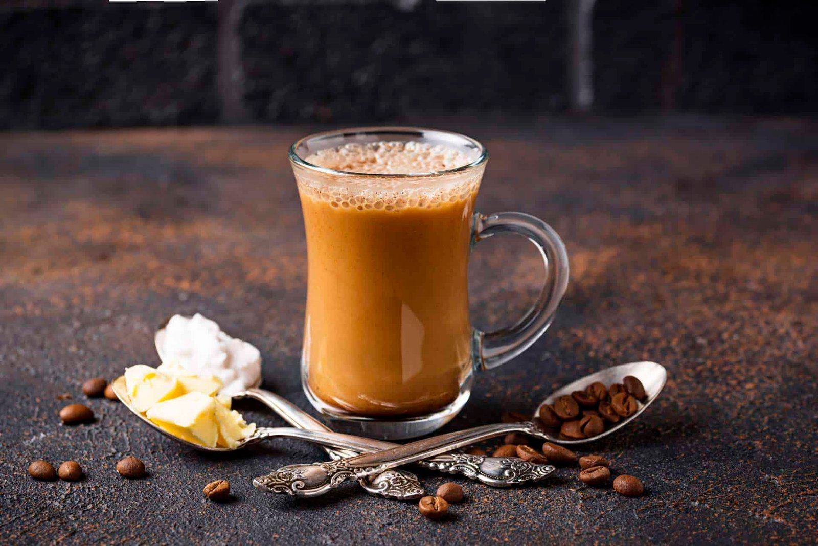 Glass mug of coffee with a spoon and coffee beans