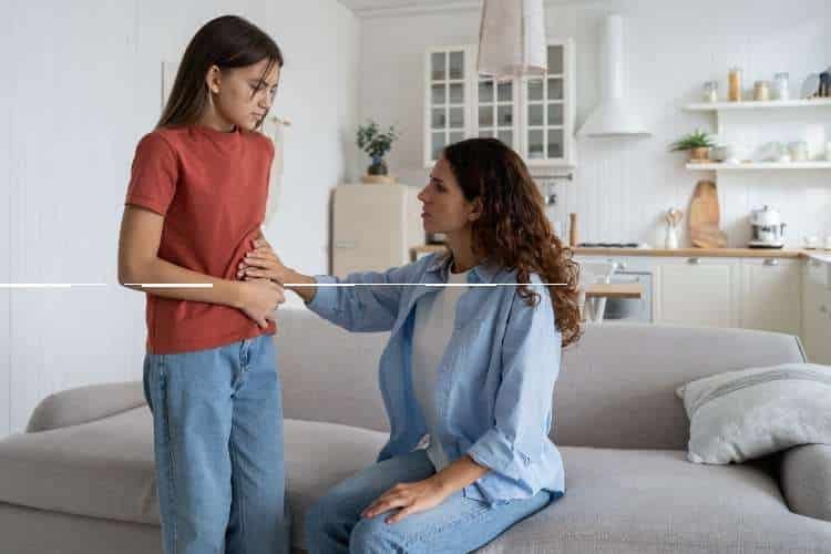 Woman with stomach pain being comforted by another woman