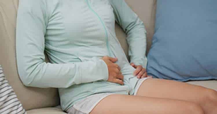 Woman on a sofa holding her stomach