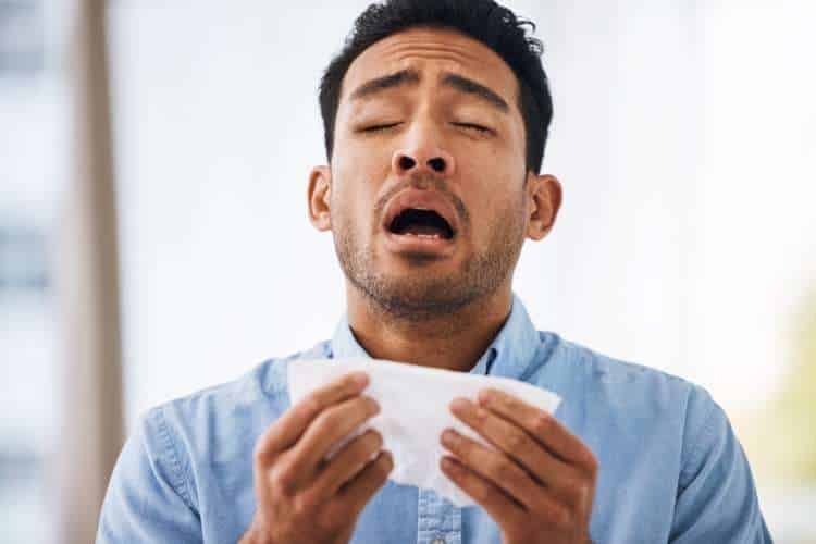 Man about to sneeze into a tissue