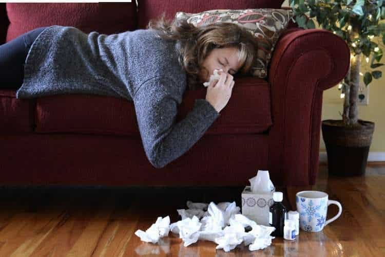 Woman lying on a sofa with tissues on the floor