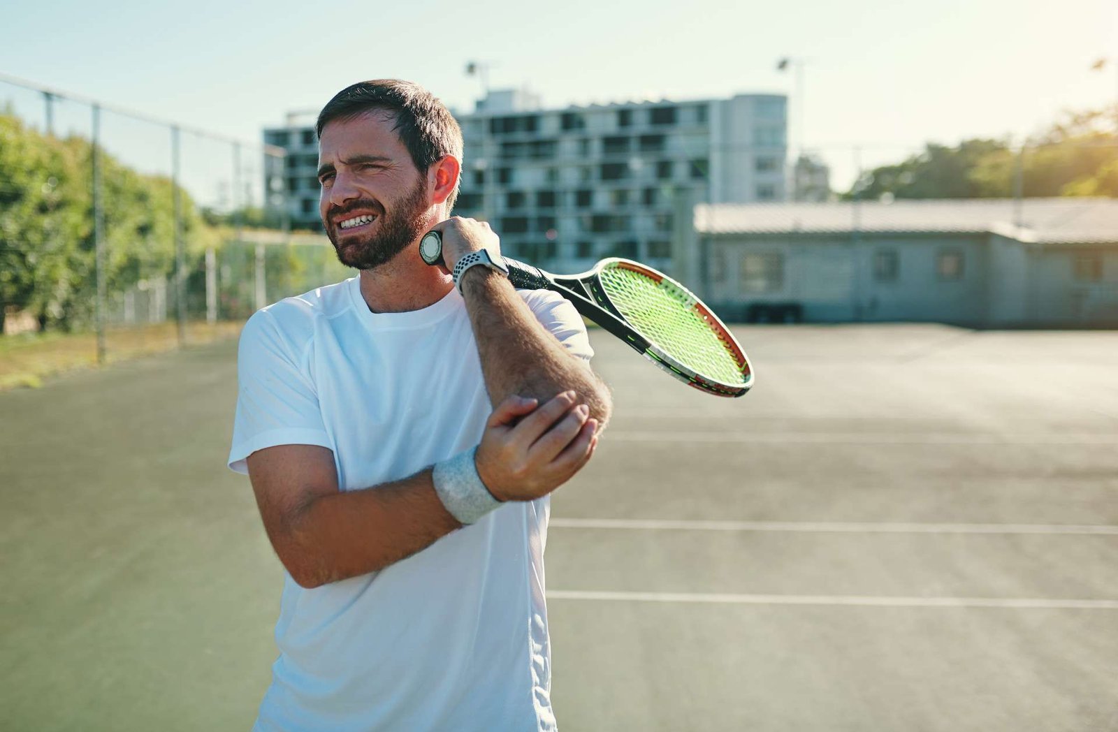 Tennis player holding his elbow on a court